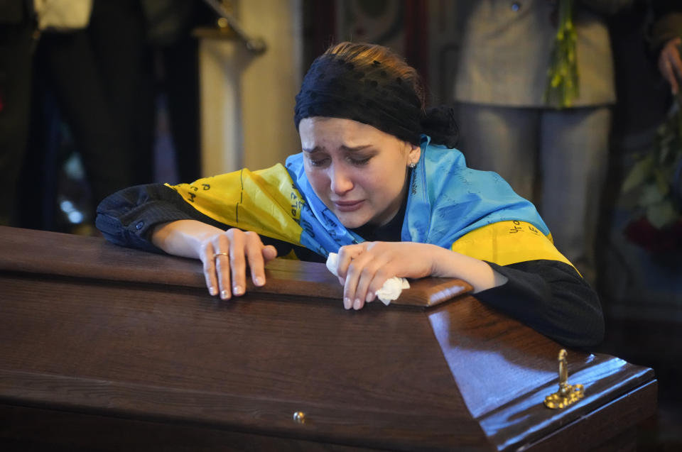 The widow cries at the coffin of volunteer soldier Oleksandr Makhov, 36 a well-known Ukrainian journalist, killed by the Russian troops, at St Michael cathedral in Kyiv, Ukraine, Monday, May 9, 2022. (AP Photo/Efrem Lukatsky)