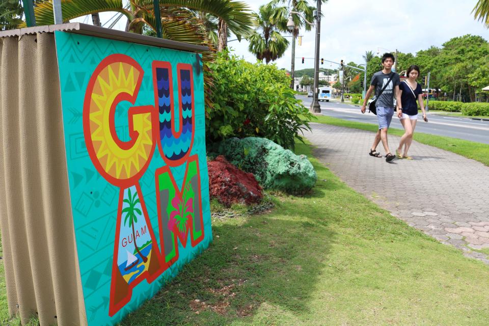 In this May 15, 2017, photo, tourists walk through a shopping district in Tamuning, Guam.