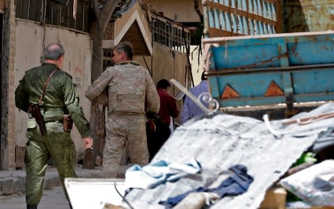 Members of the Russian military police walking amid destruction in the Eastern Ghouta town of Douma  - Credit: OUAI BESHARA/AFP/Getty Images