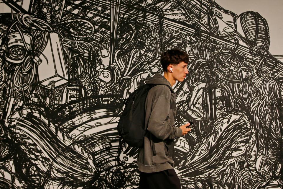 A first year UMAss Dartmouth art student walks past the giant floor and wall piece by New York based Korean Artist Heeseop Yoon at the UMass Dartmouth CVPA gallery.