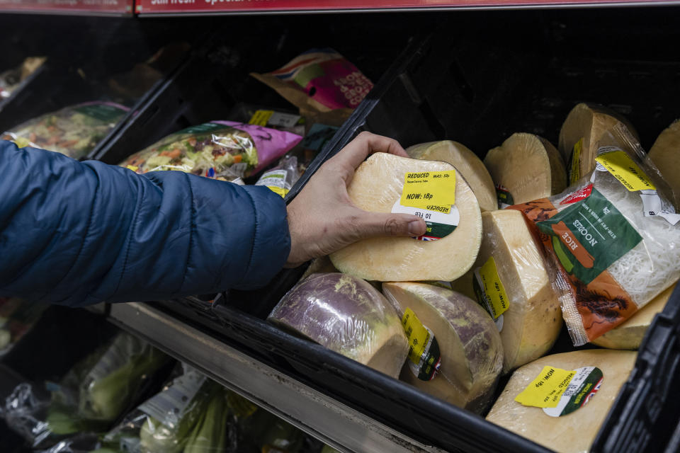 Close up of a man shopping in a supermarket while on a budget. He is looking for low prices due to inflation. He is living in the North East of England and is picking up a turnip.