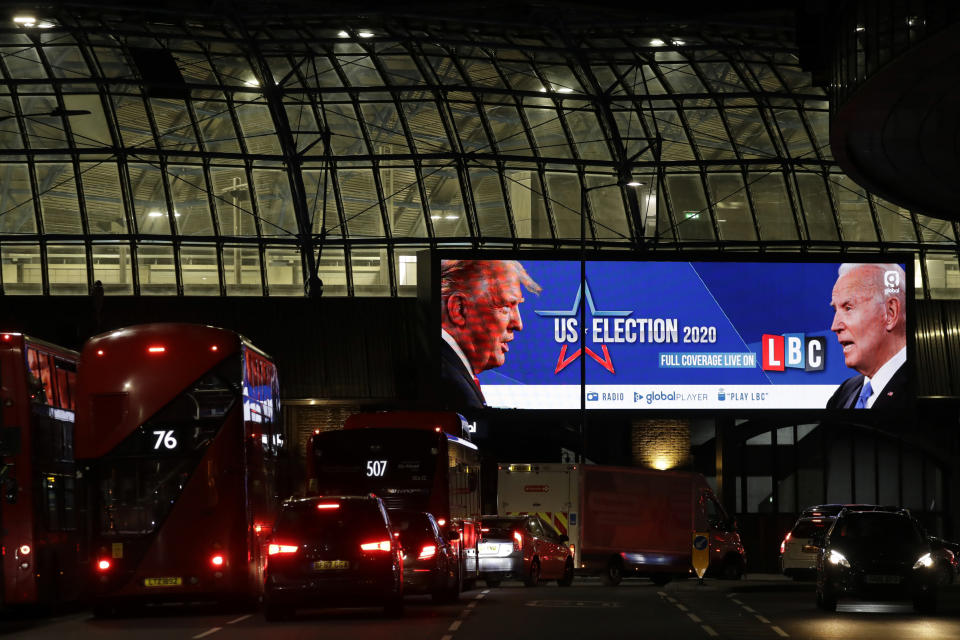 FILE - In this Nov. 2, 2020 file photo an advert screen in London, promotes the radio coverage of LBC (London Broadcasting Company) ahead of Tuesday's U.S. presidential election. If you're the leader of an increasingly isolated country, what's better — to keep an unreliable friend or gain a dependable critic? That's the dilemma facing British Prime Minister Boris Johnson over a U.S. election taking place weeks before the U.K. makes an economic split from the European Union at year's end and seeks new trade and diplomatic partners. (AP Photo/Matt Dunham, File)