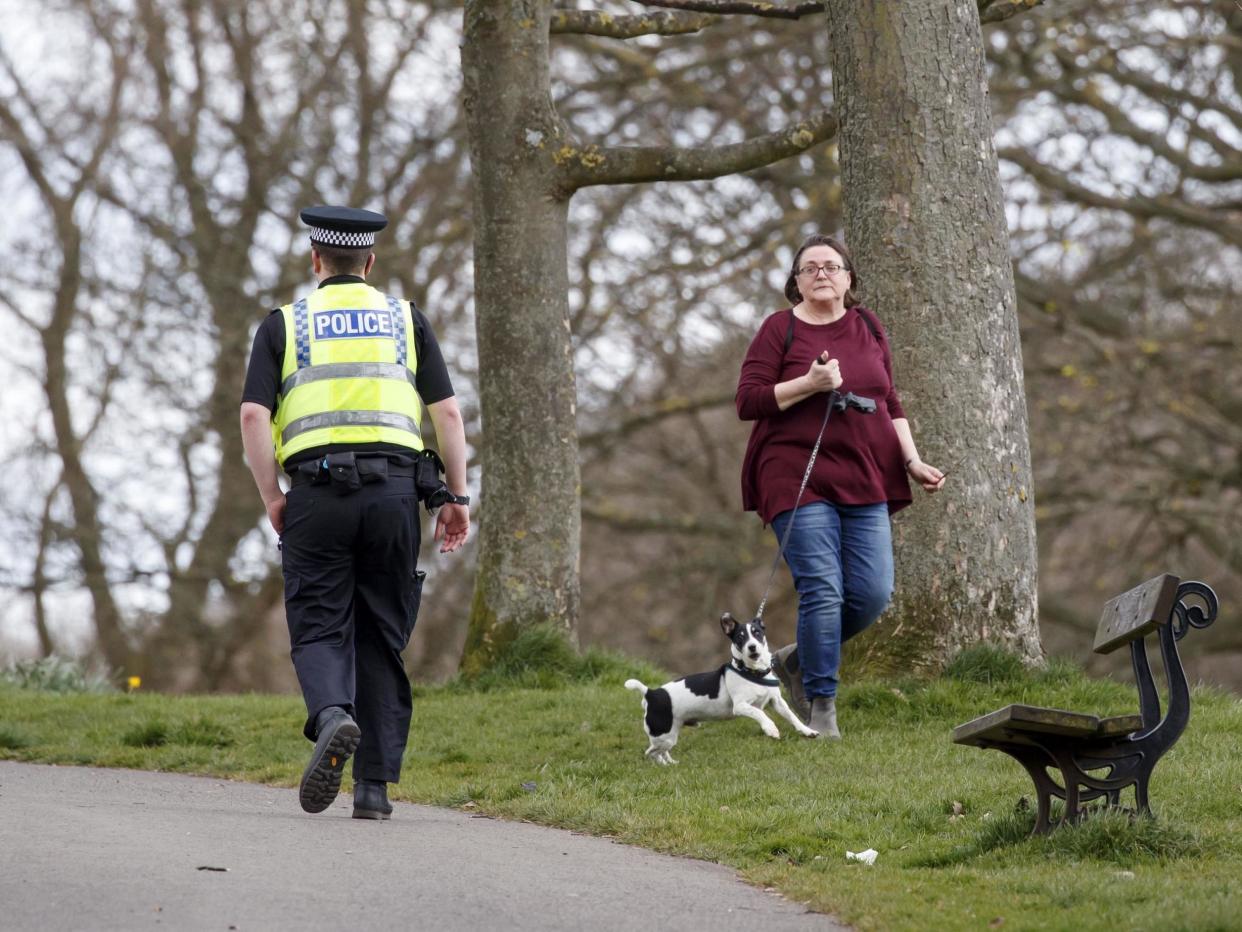 A policeman walks past a woman exercising with dog in Roundhay Park, Leeds: PA