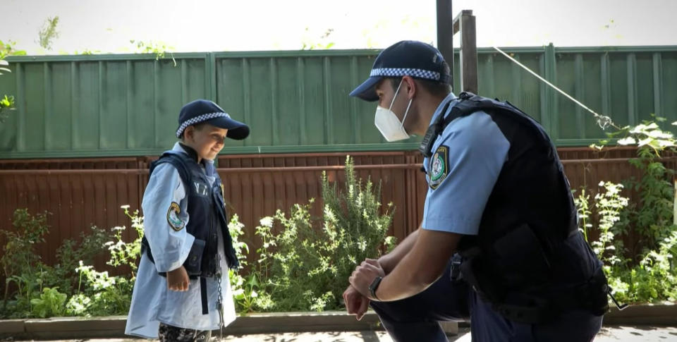 The police officer talking with the boy with leukemia after he took care of his rooster in Fairfield, Australia. Source: Newsflash/Australscope