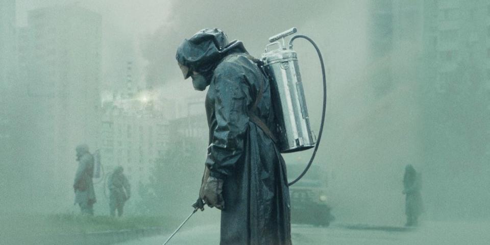 A man in a hazmat suit sprays liquid from a canister on his back