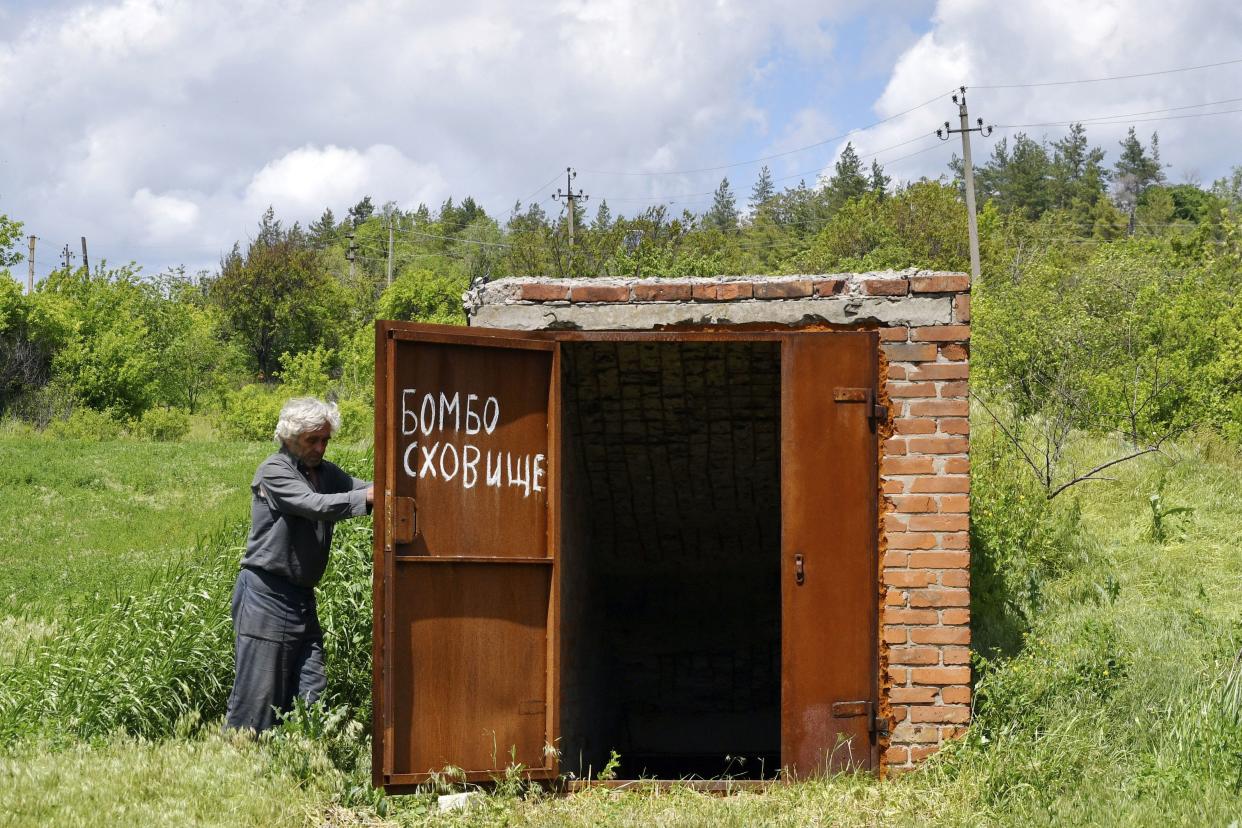 A local resident Nikolai Kononenko, 67, opens the door of a bomb shelter in the village of Mayaky, Donetsk region, Ukraine, Friday, May 27, 2022. 