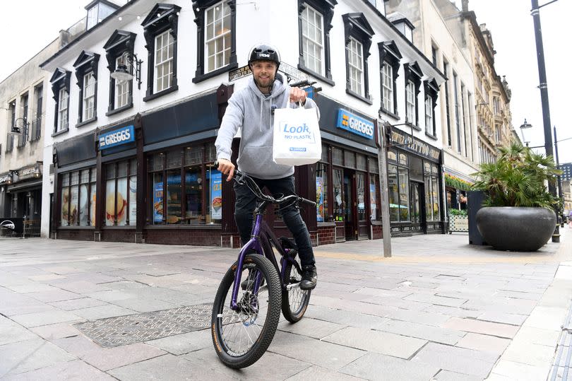 Man outside Greggs on bike.