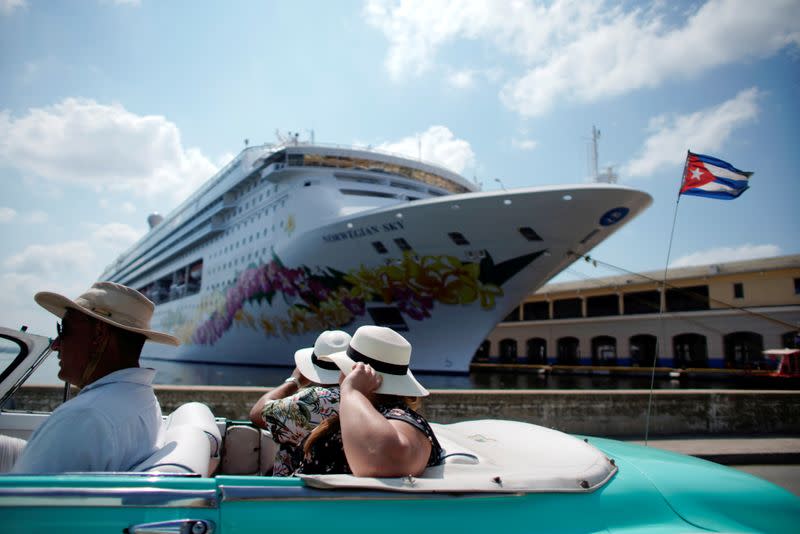 FILE PHOTO: Tourists ride inside a vintage car as they pass by the Norwegian Sky cruise ship in Havana