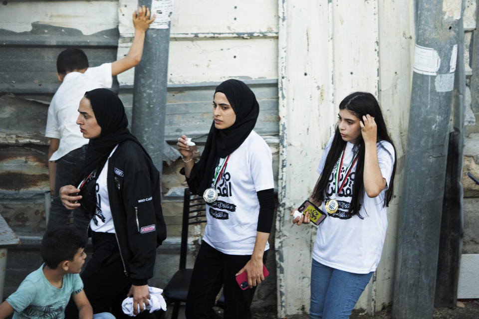 FILE - In this Friday, June 4, 2021 file photo, Palestinian activist Muna el-Kurd, center, wears a medal from a marathon as she leaves the site where Israeli police fired tear gas during clashes in the Silwan neighborhood of east Jerusalem. On Sunday, Israel arrested el-Kurd, a Palestinian protest leader in the contested Sheikh Jarrah neighborhood of Jerusalem, a day after forcefully detaining a prominent journalist there. (AP Photo/Maya Alleruzzo, File)