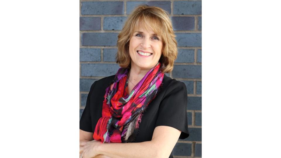 woman smiling in a colourful scarf and a black top