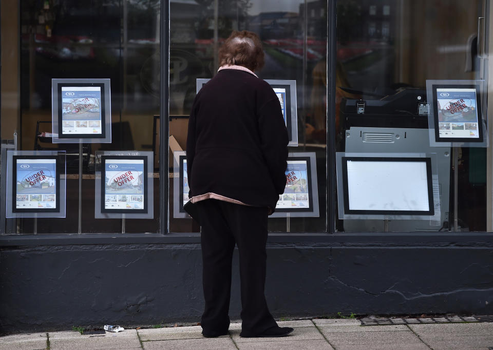 NEWCASTLE-UNDER-LYME, ENGLAND - DECEMBER 21: A lady looks at houses for sale through an estate agents window on December 21, 2021 in Newcastle-Under-Lyme, England. (Photo by Nathan Stirk/Getty Images)