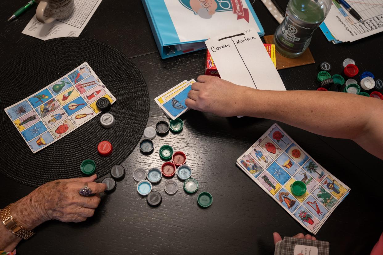 Marlene Carrasca (der.) juega lotería con Carmen García, a quien cuida, en su apartamento de Phoenix, el 6 de septiembre de 2023.