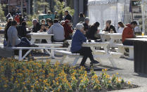 Customers enjoy lunch in the sunshine at the Riverside Market in Christchurch, New Zealand, Sunday, Aug. 9, 2020. New Zealand marked a 100 days of being free from the coronavirus in its communities Sunday, Aug. 9, with just a handful of infections continuing to be picked up at the border where people are quarantined. (AP Photo/Mark Baker)