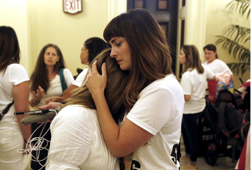 Michelle Sabino, left, is hugged by Melissa Floyd, right, who are both opponents of the recently passed legislation to tighten the rules on giving exemptions for vaccinations, console each other after the Legislature approved a companion measure, the Capitol in Sacramento, Calif., Monday, Sept. 9, 2019. Gov. Gavin Newsom signed both bills, Monday. Both women say they had infant children injured by vaccinations. (AP Photo/Rich Pedroncelli)