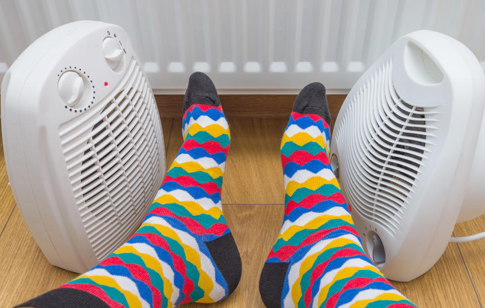 Feet in bright multicolored socks near heaters at home. Symbolic image of home heating in the cold winter season. Close-up, selective focus.