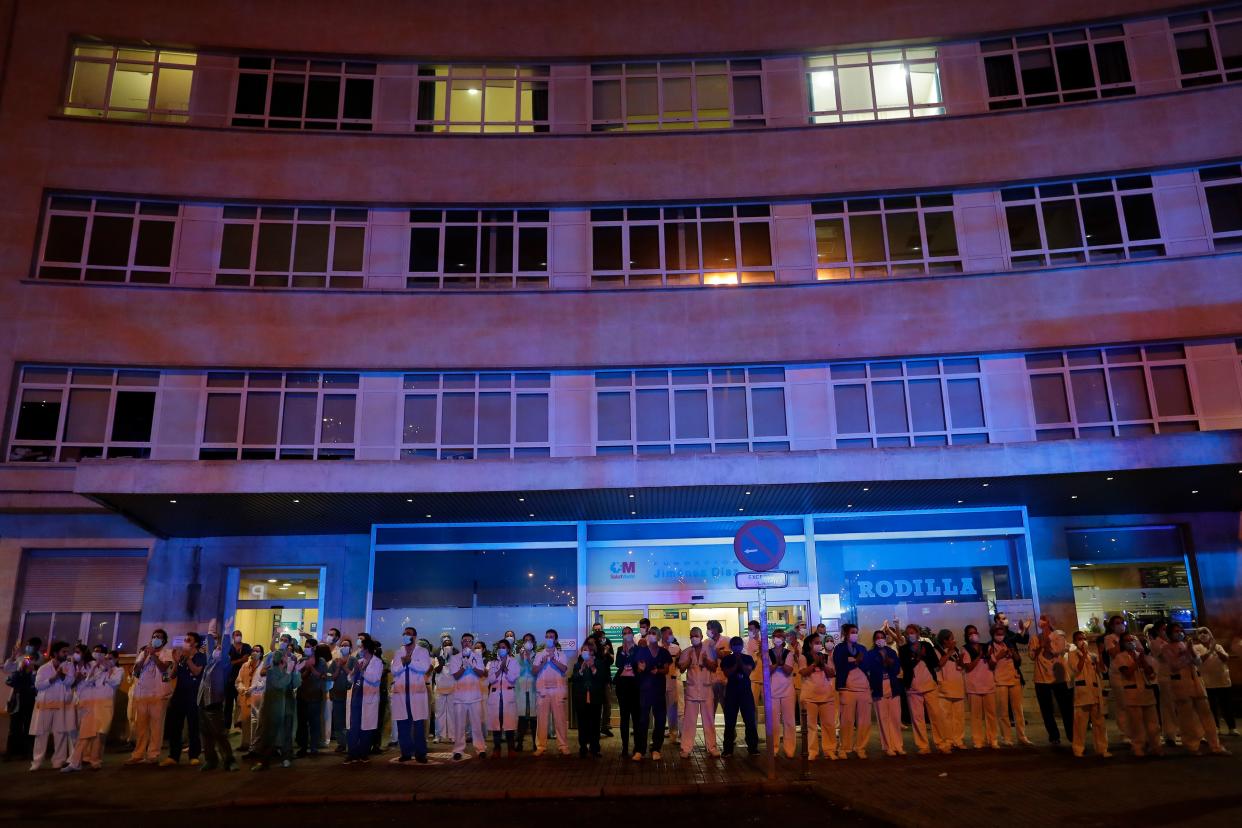 Health workers react as people applaud from their nearby houses in support of the medical staff that are working on the COVID-19 virus outbreak at the Jimenez Diaz Foundation University hospital in Madrid, Spain, on Saturday, March 21, 2020.