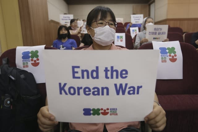 An anti-war activist holds a card (Ahn Young-joon/AP)