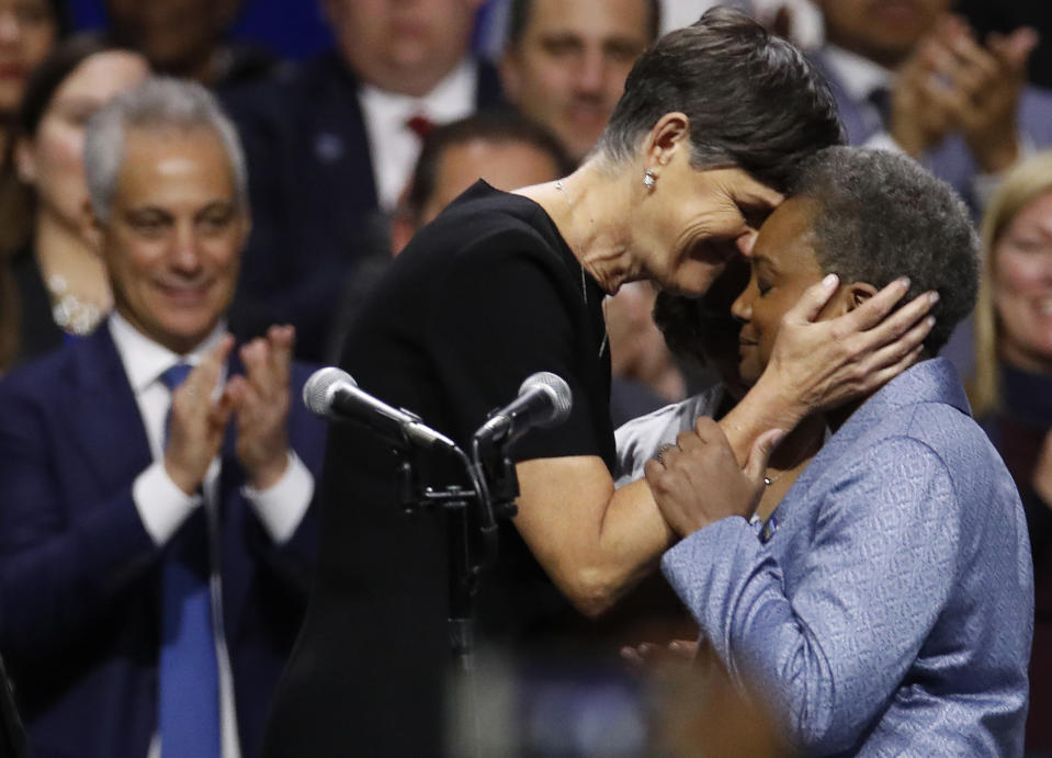 Mayor of Chicago Lori Lightfoot, right, embraces her spouse Amy Eshleman as outgoing Mayor Rahm Emanuel looks on during her inauguration ceremony Monday, May 20, 2019, in Chicago. (AP Photo/Jim Young)