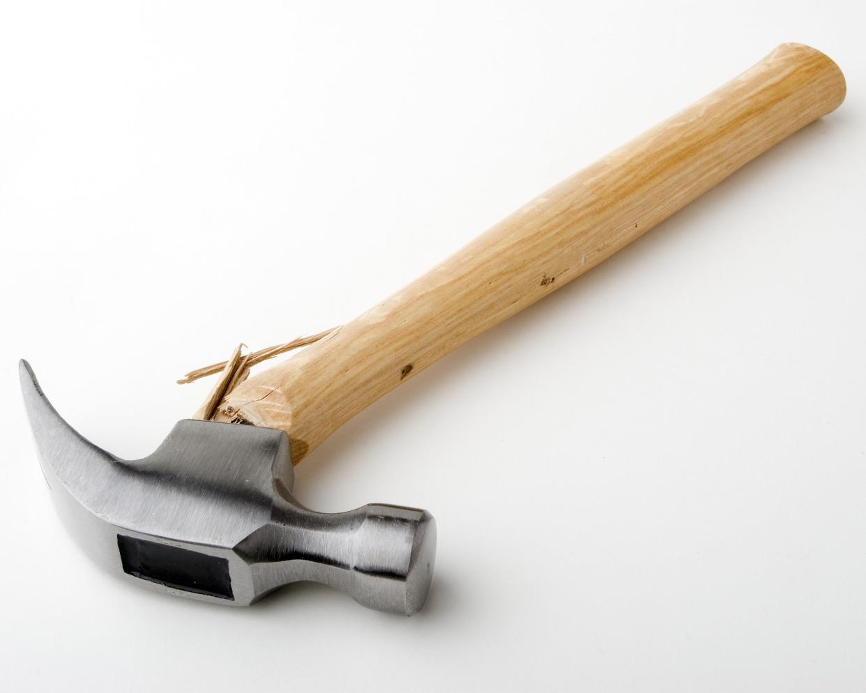 Hammer with the metal head broken off the wooden handle, laid down on a light grey to white gradient background