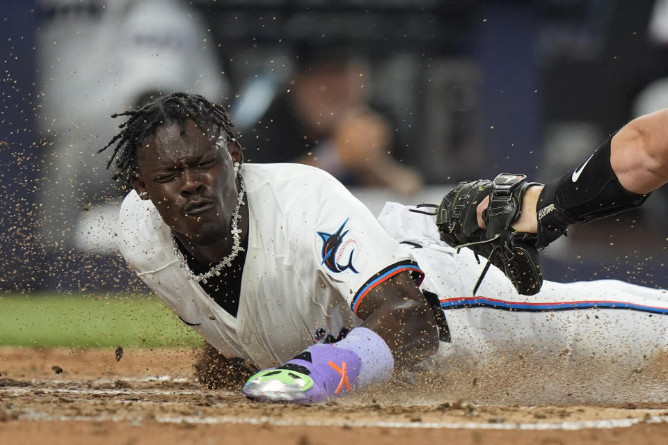 Miami Marlins' Jazz Chisholm Jr., left, scores as Pittsburgh Pirates catcher Henry Davis (32) attempts the tag, during the third inning of a baseball game, Thursday, March 28, 2024, in Miami. Bryan De La Cruz also scored on the single by Jake Burger. (AP Photo/Wilfredo Lee)