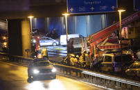 Forensic experts are investigating a car at the city motorway A100 after an accident in Berlin, Germany, Tuesday, Aug. 18, 2020. According to German news agency dpa, prosecutors say the series of crashes caused by a 30-year-old Iraqi man on the highway was an Islamic extremist attack. (Paul Zinken/dpa via AP)