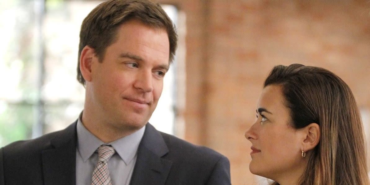 dinozzo and ziva in ncis, standing close and sharing a smirk in an indoor environment