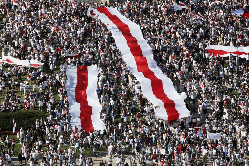 ARCHIVO - En esta foto de archivo del 16 de agosto de 2020, manifestantes contra el gobierno, con enormes banderas nacionales, se concentran en el centro de Minsk, la capital, para reclamar la renuncia del presidente Alexander Lukashenko, en el poder desde hace 26 años, luego de unas elecciones que consideran amañadas. (AP Foto/Dmitri Lovetsky, File)