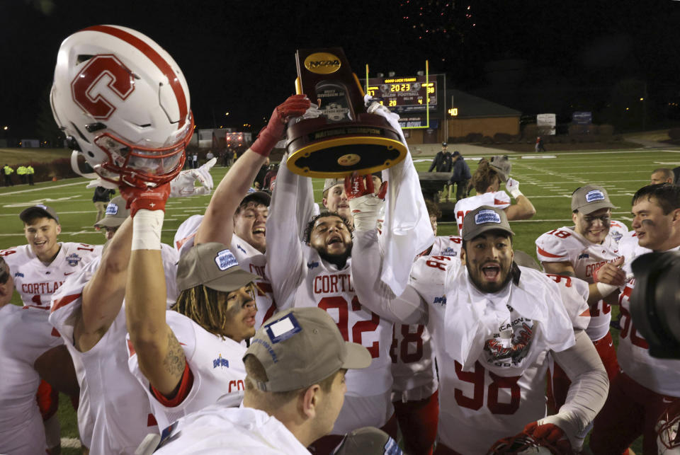 Cortland players celebrate with the trophy after defeating North Central in the Amos Alonzo Stagg Bowl NCAA Division III championship football game in Salem, Va., Friday Dec. 15, 2023. (Matt Gentry/The Roanoke Times via AP)