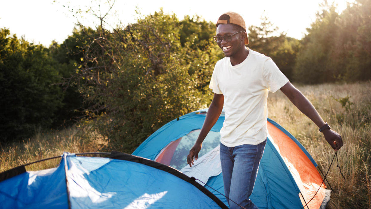  Young casually clothed man setting up tent. 