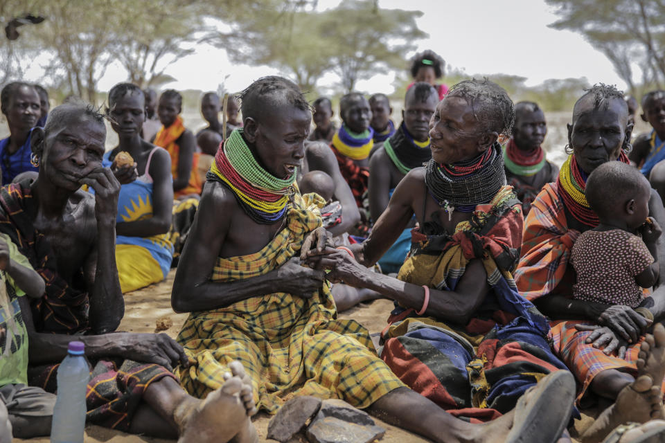 A woman hesitates to share a piece of palm fruit with her friend, during a visit by United Nations Under-Secretary-General for Humanitarian Affairs Martin Griffiths, in the village of Lomoputh in northern Kenya Thursday, May 12, 2022. Griffiths visited the area on Thursday to see the effects of the drought which the U.N. says is a severe climate-induced humanitarian emergency in the Horn of Africa. (AP Photo/Brian Inganga)