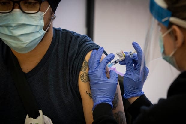 Personal support worker Michael Gellizeau gets his COVID-19 vaccine from nurse practitioner Victoria Pierri at a vaccine clinic for care-home workers put on by the University Health Network, in Toronto, on Dec. 15, 2020. 