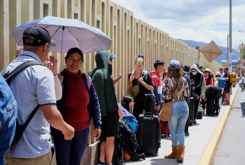 Passengers stand in line outside the airport, in Cuzco