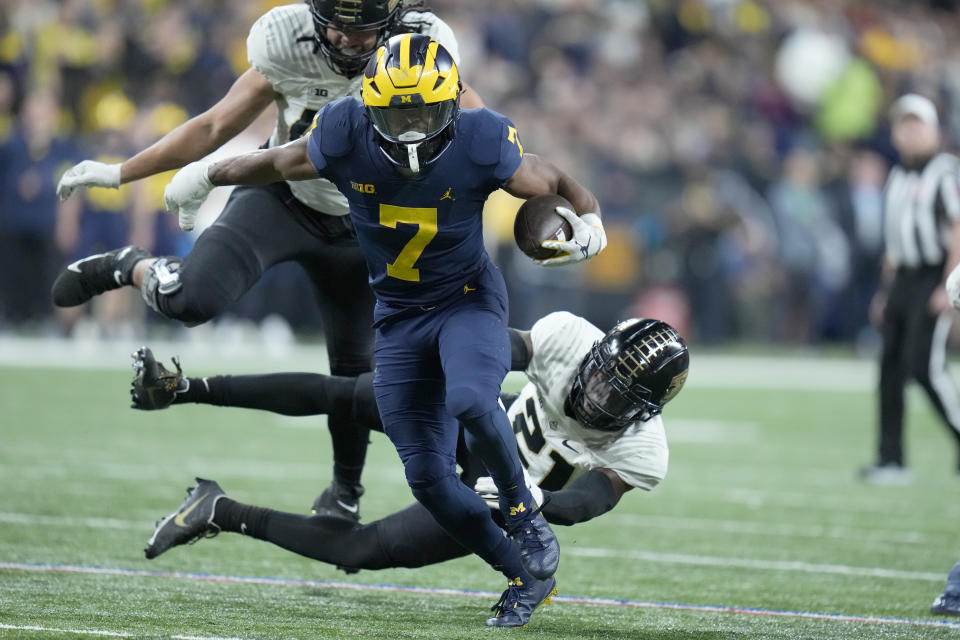 Michigan running back Donovan Edwards (7) runs with the ball as Purdue safety Sanoussi Kane (21) defends during the second half of the Big Ten championship NCAA college football game, Saturday, Dec. 3, 2022, in Indianapolis. (AP Photo/Michael Conroy)