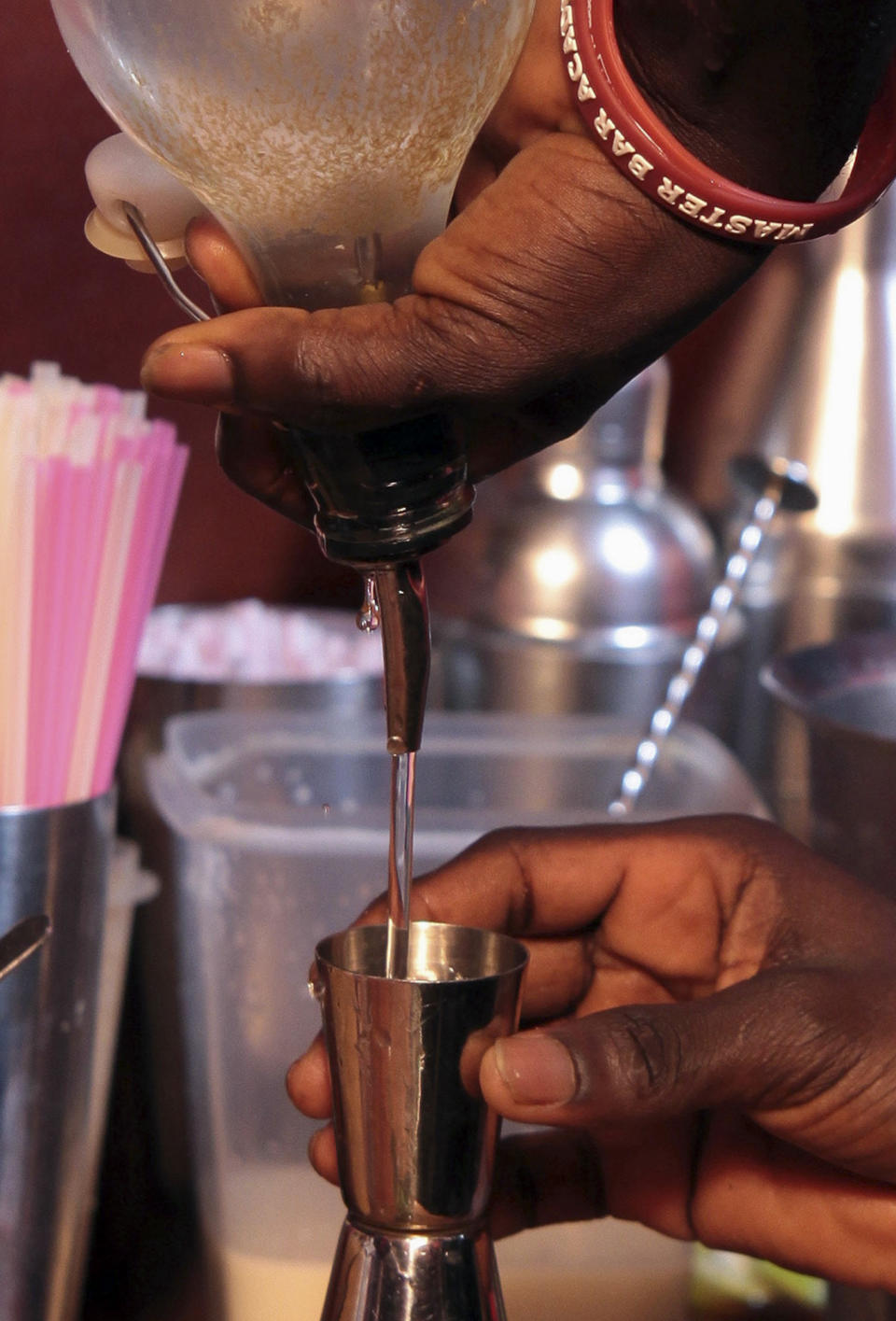 In this Tuesday, June 18, 2013 photo, a bartender pours out a measure of local spirit akpeteshie as he prepares a cocktail, at The Republic, in Accra, Ghana. In Ghana, the local alcohol akpeteshie tastes like fire to the uninitiated, burning all the way down the throat to a nervous stomach. But at The Republic in the nation’s capital, it comes garnished with mint and brown sugar for young professionals just getting off work. The drinks here represent part of a new drink movement in Ghana that some hope will spread across West Africa, taking traditional liquors and bringing them out of the countryside and into capital nightclubs. (AP Photo/Christian Thompson)