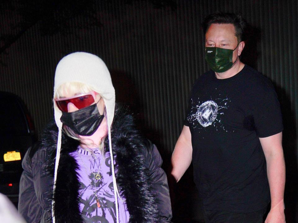 Grimes and Elon Musk wearing masks and walking to a car in New York City