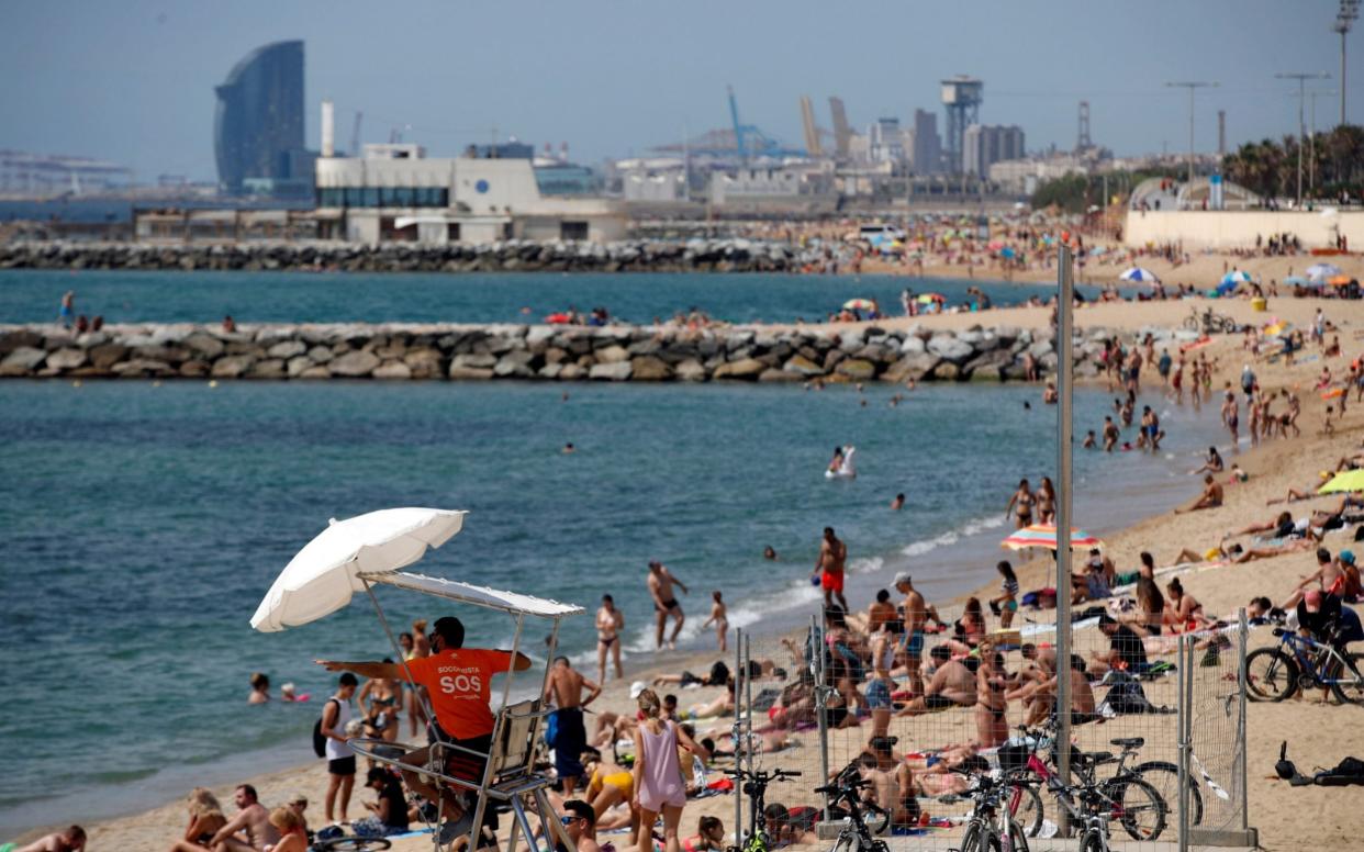 People enjoy sunny weather at the beach in Barcelona