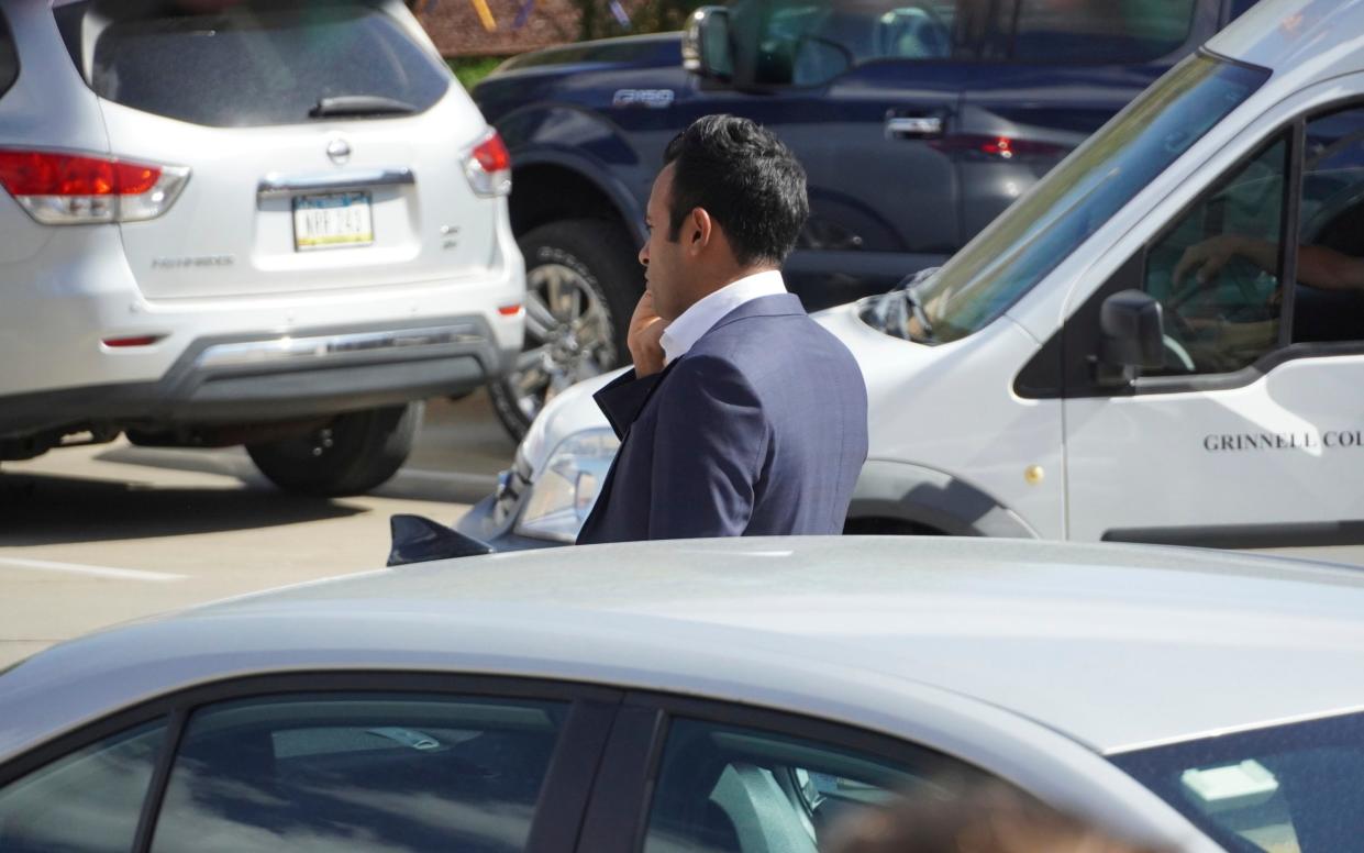 Mr Ramaswamy pictured on the phone while viewing the damage to one of his campaign vehicles