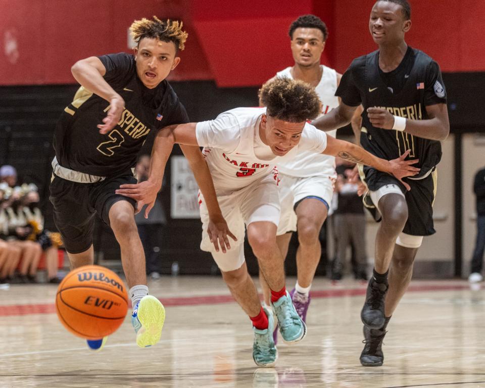 Oak Hills' Johnny Castellanos, center, chases a loose ball with Hesperia's Jordan Malveaux, left, and King Allah during their game Friday, Jan. 21, 2022.