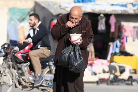 A man eats food that was distributed as aid in a rebel-held besieged area in Aleppo, Syria November 6, 2016. REUTERS/Abdalrhman Ismail/File Photo