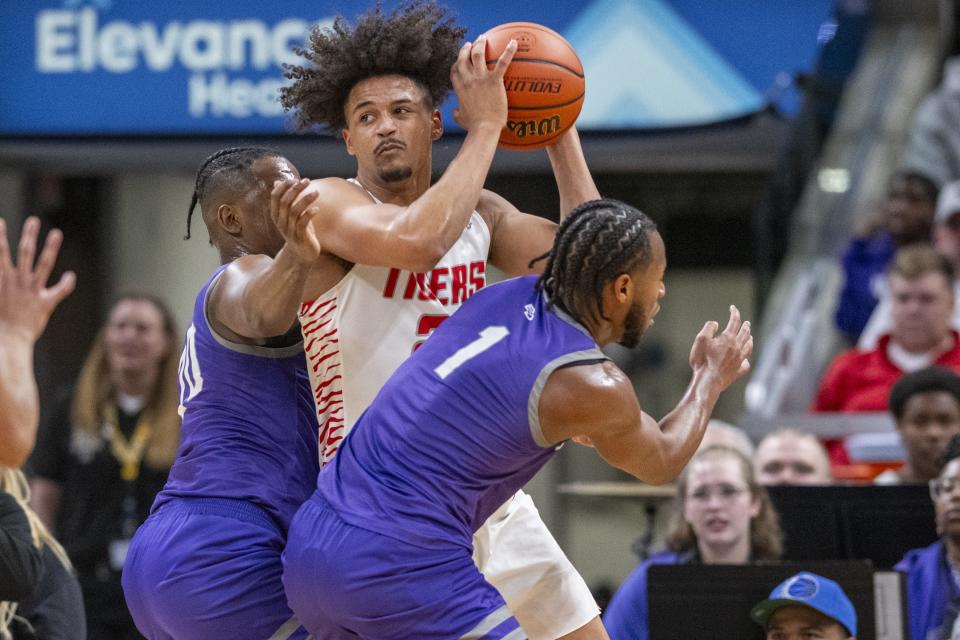 Fishers High School senior Keenan Garner (23) is trapped along the baseline by the defense of Ben Davis High School seniors Ramone Enis, left, and Mark White (1) during the first half of an IHSAA class 4A state championship basketball game, Saturday, March 30, 2024, at Gainbridge Fieldhouse.