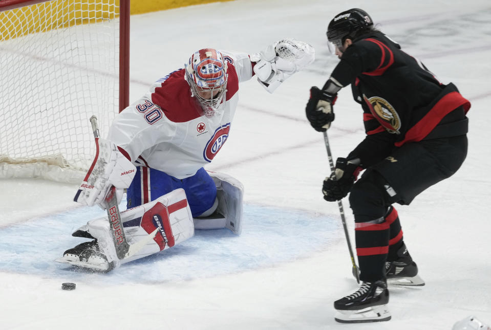 Montreal Canadiens goaltender Cayden Primeau, left, kicks out the puck under pressure from Ottawa Senators right wing Zack MacEwen, right, during first-period NHL hockey game action Thursday, Jan. 18, 2024, in Ottawa, Ontario. (Adrian Wyld/The Canadian Press via AP)