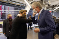 Actor Lin-Manuel Miranda, center, and New York Mayor Bill de Blasio, bump elbows before they tour the grand opening of a Broadway COVID-19 vaccination site intended to jump-start the city's entertainment industry, in New York, Monday, April 12, 2021. At left is Miranda's father, Luis A. Miranda, Jr. (AP Photo/Richard Drew, Pool)