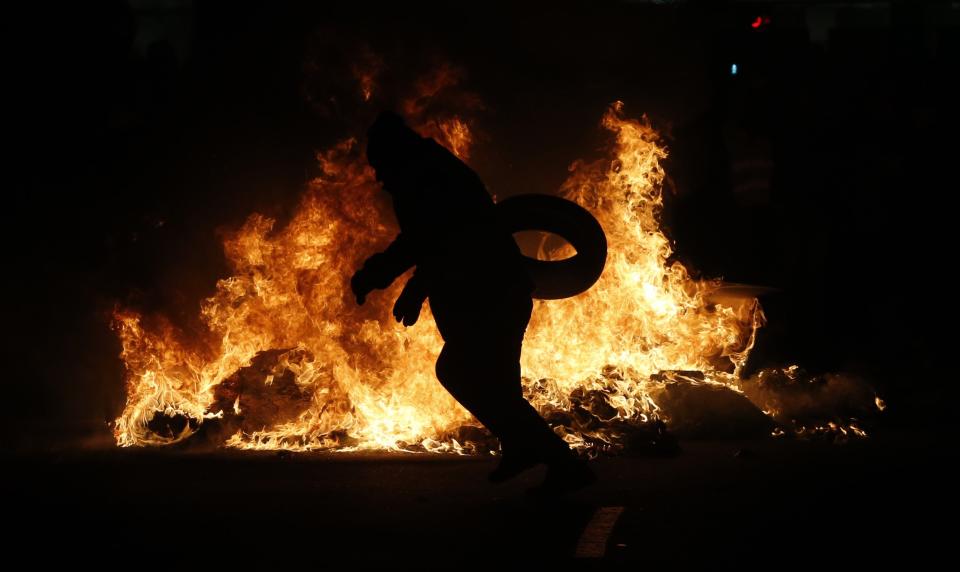 <p>Un manifestante arroja un neumático en la hoguera generada por los taxistas. (Foto: Javier Lizón / EFE). </p>