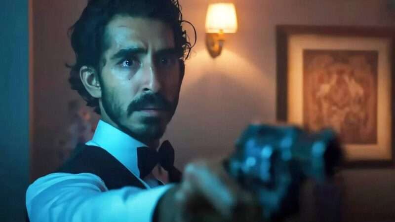 Dev Patel's character in 'Monkey Man' pointing a gun at the camera