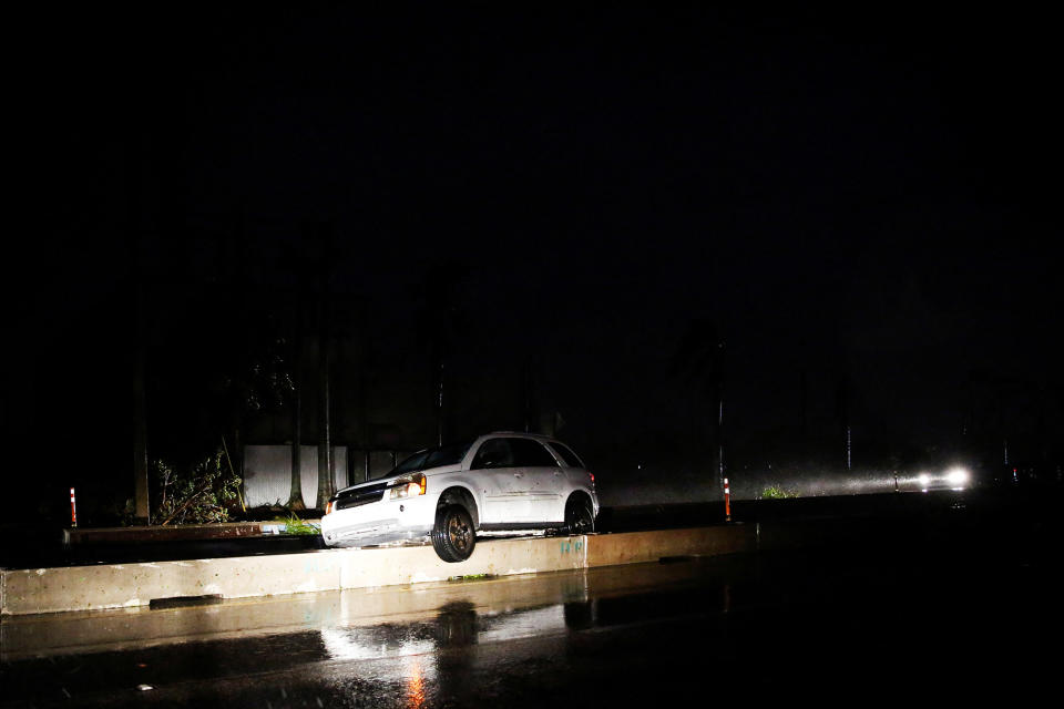 A car is stranded on the median blockade of a street in Fort Myers on Sept. 28, 2022.