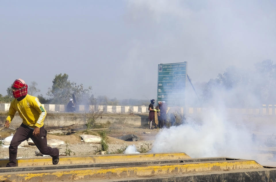 A man runs for cover after police fired tear gas at protesting farmers near Shambhu border that divides northern Punjab and Haryana states, almost 200 km (125 miles) from New Delhi, India, Wednesday, Feb.14, 2024. Protesting Indian farmers Wednesday clashed with police for a second consecutive day as tens of thousands of them tried to march to the capital New Delhi to demand guaranteed crop prices for their produce. (AP Photo/Rajesh Sachar)