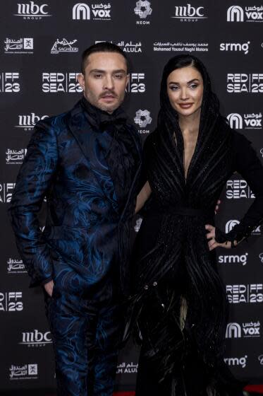 Ed Westwick and Amy Jackson dressed in dark formalwear pose together for a photo at a film festival