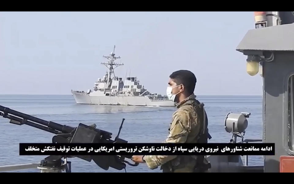 This frame grab from a video released by Iran's paramilitary Revolutionary Guard on Wednesday, Nov. 3, 2021, shows a Guard soldier on a speed boat in front of a U.S warship amid the seizure of a Vietnamese-flagged oil tanker in the Gulf of Oman. Iran seized the tanker in the Gulf of Oman last month and still holds the vessel, two U.S. officials told The Associated Press on Wednesday, revealing the latest provocation in Mideast waters as tensions escalate between Iran and the United States over Tehran's nuclear program. (Revolutionary Guard via AP)