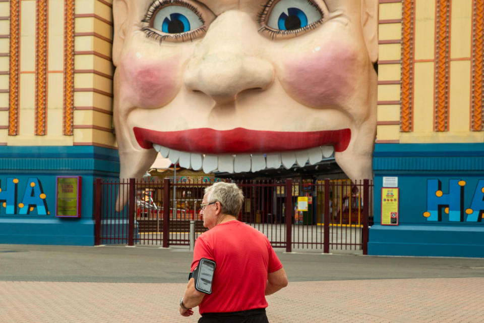  A man is seen jogging past a closed Luna Park in Sydney.