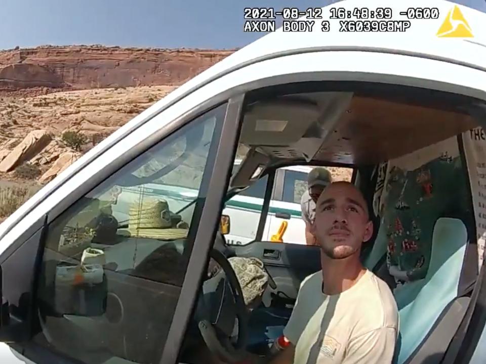 A Utah police officer's bodycam view of Brian Laundrie in the drivers' seat of a van. Laundrie is looking up at the officer.
